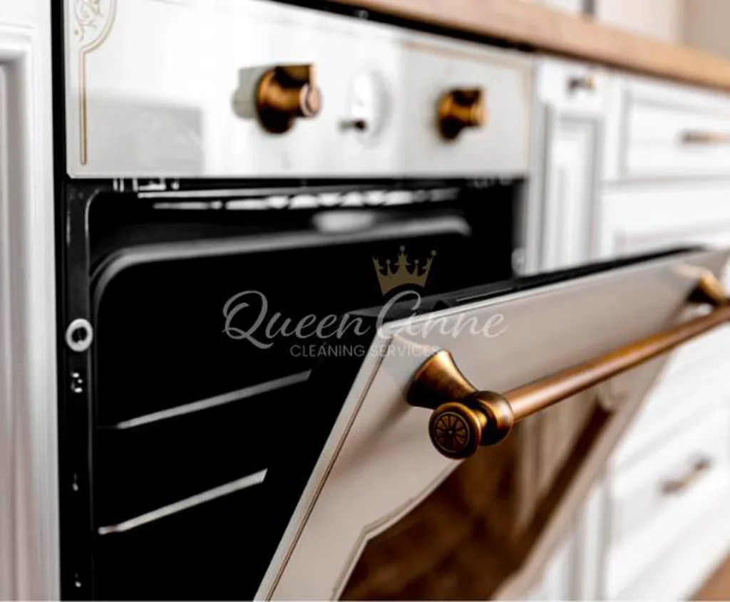 White vintage-style oven with an open door and metallic knobs, located in a modern kitchen, featuring a logo "Queen Anne Cleaning Services," specializing in deep cleaning and house cleaning in Seattle.